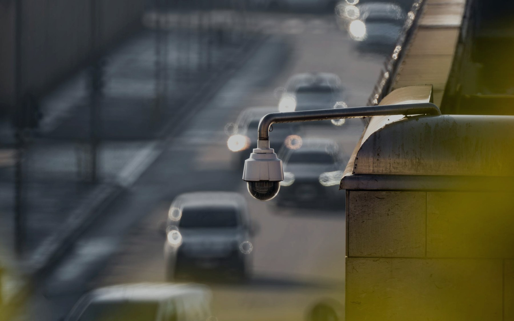 Street surveillance camera in sharp focus with a blurred traffic background.
