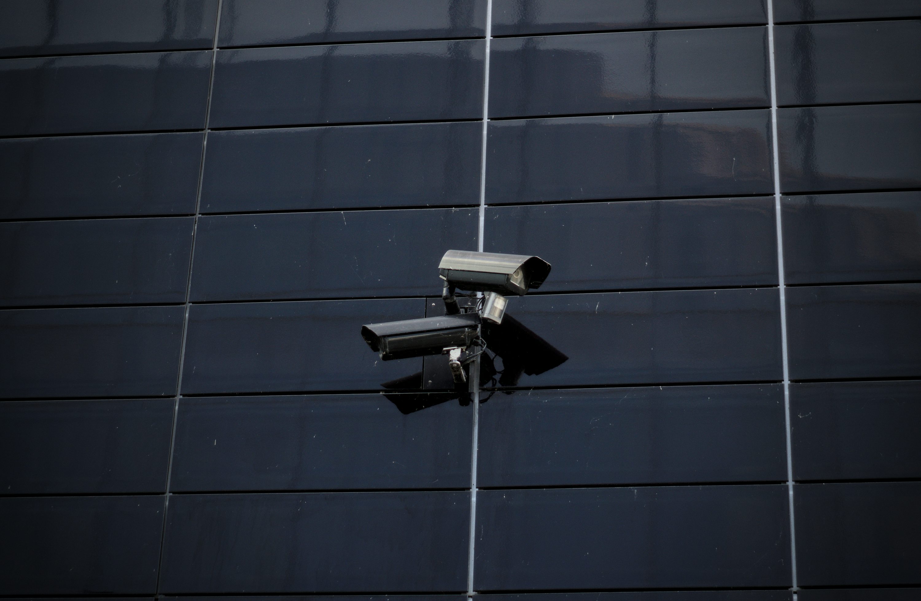 Mounted surveillance cameras on a dark exterior wall.